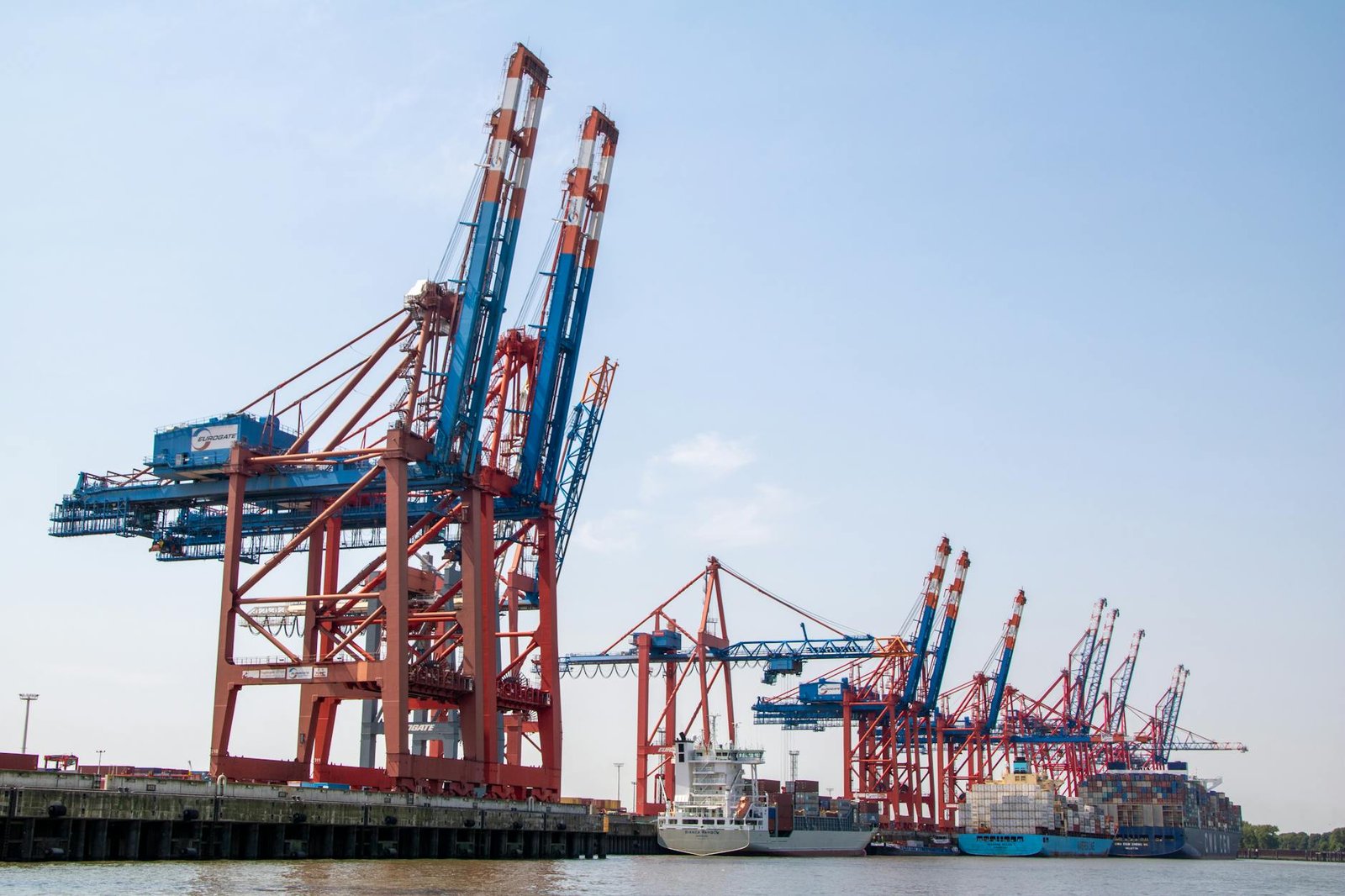 A clear view of shipping cranes at the bustling Hamburg Port on a sunny day.